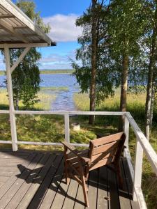 un banco de madera sentado en una terraza con vistas al lago en Svens Stuga en Burträsk