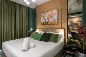 een slaapkamer met een groot wit bed met groene accenten bij The Shell House in Tel Aviv