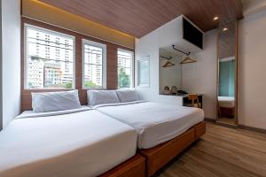 1 dormitorio con 1 cama blanca grande y ventanas en The Period Pratunam, en Bangkok