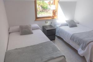 1 Schlafzimmer mit 2 Betten und einem Fenster in der Unterkunft Casa con jardín y gran terraza con vistas al mar in Cangas