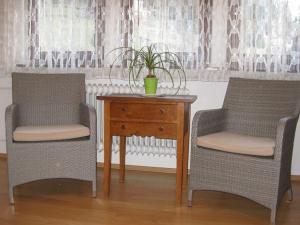 Dos sillas y una mesa con una maceta. en Haus Mühlgrund, en Bad Wildbad