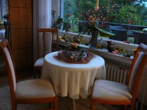 einen Tisch mit einem weißen Tischtuch und Stühlen sowie ein Fenster in der Unterkunft Haus Drei Tannen in Schieder-Schwalenberg