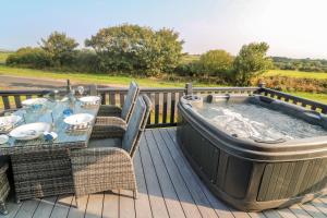 a hot tub on a deck with a table and chairs at Chantry Lodge in Newquay