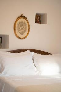 a bed with white sheets and a picture on the wall at Castello di Haria in Kaloú