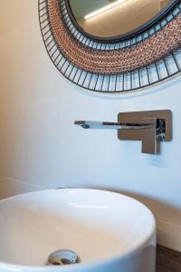 een wastafel in de badkamer met een kraan en een spiegel bij Hang Loose Cottage in Gizzeria