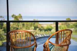 - deux chaises assises sur un balcon donnant sur l'océan dans l'établissement Hang Loose Cottage, à Gizzeria