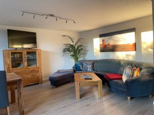 a living room with a blue couch and a table at Ferienwohnung Elfengast, FassSauna, Harzurlaub in bester Lage in Bad Harzburg