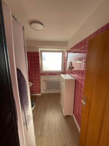 un baño pequeño con lavabo y paredes de azulejos rojos. en Ferienwohnung Elfengast, FassSauna, Harzurlaub in bester Lage en Bad Harzburg