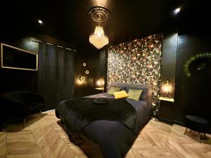 a bedroom with a large bed and a chandelier at Love Room Secrète Les Petits Plaisirs in Angers