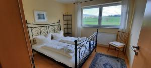 a bedroom with a bed with white sheets and a window at Panoramablick in Rettenberg