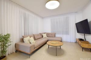 a living room with a couch and a tv at וילת קסם הזוהר- ניר יפה in Nir Yafe