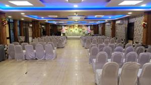 an empty hall with chairs and a stage in the background at Hotel Vilas, Prayagraj in Allahābād