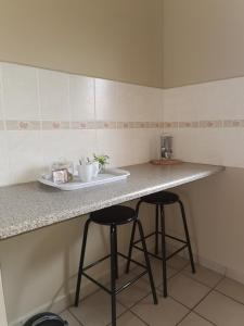 a kitchen with two bar stools and a counter at At Home BB in Estcourt