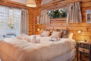 uma grande cama branca num quarto com paredes de madeira em Cabañas Bahiamia em Villa Pehuenia