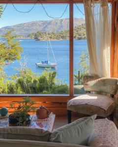 um quarto com uma grande janela com um barco na água em Cabañas Bahiamia em Villa Pehuenia