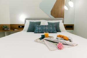 Una cama con dos toallas y una bandeja de comida. en Magico Suites City Heart Luxury Appartments, en Alexandroupoli