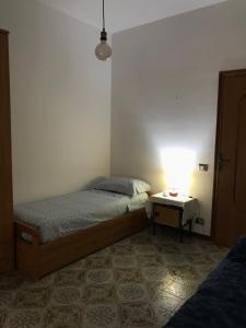 1 dormitorio con 1 cama y 1 mesa con lámpara en Casa Mariano IV (IUN Q8167), en Oristano