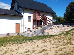 ein weißes Haus mit einer Steinmauer und einer Treppe in der Unterkunft Agroturystyka A&G Dubeninki in Dubeninki