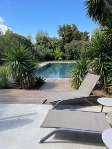 a swimming pool with two lounge chairs next to it at Le Mas de la Dame in Saint-Tropez