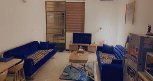 uma sala de estar com sofás azuis e uma televisão em Dreams Apartments شقق الاحلام em Bagdá