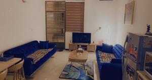 a living room with blue couches and a tv at Dreams Apartments شقق الاحلام in Baghdād