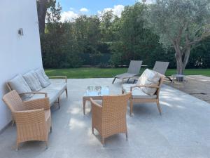 patio con sillas de mimbre, mesa y sofá en Le Mas de la Dame, en Saint-Tropez