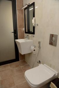 y baño con aseo, lavabo y espejo. en Syros Hotel Erbil City Center en Erbil
