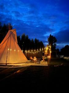 a white tent is lit up at night at Comfort Tipi Marie, Tipi Bo Deluxe & tent Nicolaï - 'Glamping in stijl' in Lembeke