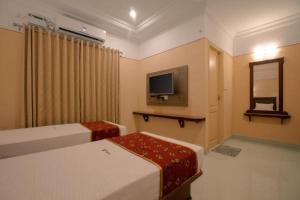 a hotel room with two beds and a tv at Hotel Vashanth Krishna in Nāgercoil