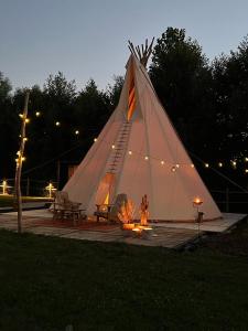 a woman is standing in a large white tent at Comfort Tipi Marie, Tipi Bo Deluxe & tent Nicolaï - 'Glamping in stijl' in Lembeke