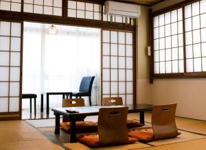 a table and chairs in a room with windows at Guesthouse Sunline Beppu in Beppu
