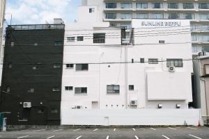別府市にあるゲストハウスサンライン別府の日焼け剤の看板が付いた白い建物