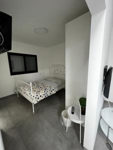 Dieses weiße Zimmer verfügt über ein Bett und einen TV. in der Unterkunft נוף לחרמון in Kibbuz Dafna