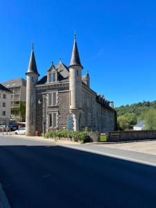 um antigo edifício de pedra com torres numa rua em Charmant appartement RDC familial ou pour le travail em Uzerche