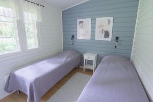 2 camas en una habitación con paredes y ventanas azules en Lomaperkkiö Cottages, en Kajaani