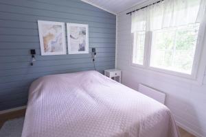 1 dormitorio con cama blanca y ventana en Lomaperkkiö Cottages, en Kajaani