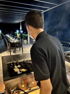 un hombre cocinando comida en una parrilla en un restaurante en S Resort El Nido en El Nido