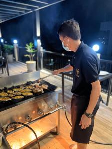 Um homem está a cozinhar comida numa grelha. em S Resort El Nido em El Nido