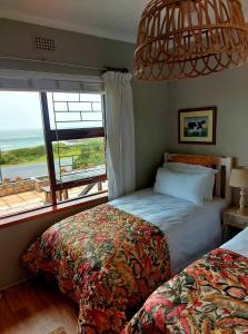 a bedroom with two beds and a large window at La Mer Seafront Selfcatering Accommodation Kleinmond in Kleinmond