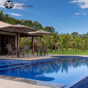 uma piscina com cadeiras e guarda-sóis ao lado de um resort em Estancia Jacy em Alto Paraíso de Goiás