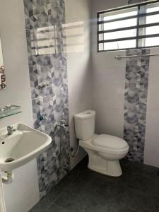 ein Bad mit einem WC und einem Waschbecken in der Unterkunft Homestay Maryam in Lumut