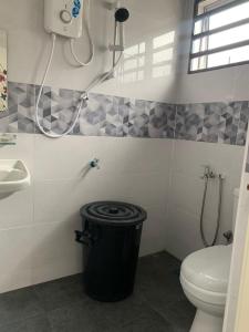 a bathroom with a toilet and a sink and a trash can at Homestay Maryam in Lumut