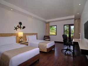 a hotel room with two beds and a desk at Holiday Inn Resort Goa, an IHG Hotel in Cavelossim