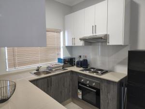 a kitchen with white cabinets and a stove top oven at Sarona city Habitat Alpha apartments C202 Gaborone in Gaborone