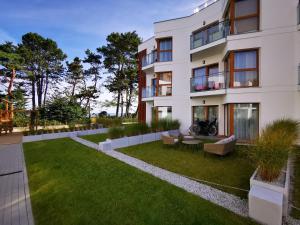 a large white building with a grass yard at Gold Apartment B29 Let's Sea Baltic Park Gąski in Gąski
