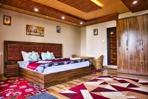 a bedroom with a large wooden bed with a red rug at Traditional Hotel & Restaurant in Darjeeling