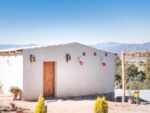 une maison blanche avec une porte dans le désert dans l'établissement Cabaña Paraíso Cachi, à Cachí