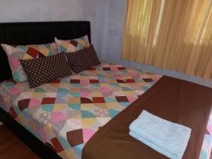 a bed with a colorful quilt and pillows on it at Juda Homestay in Banyuwangi