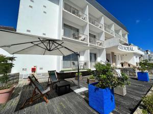 a building with an umbrella and chairs on a deck at Hôtel Ker-Noyal Quiberon Plage in Quiberon