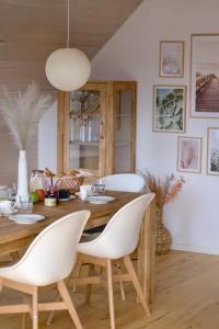 a dining room with a wooden table and white chairs at Frühlingsbogen in Harrislee